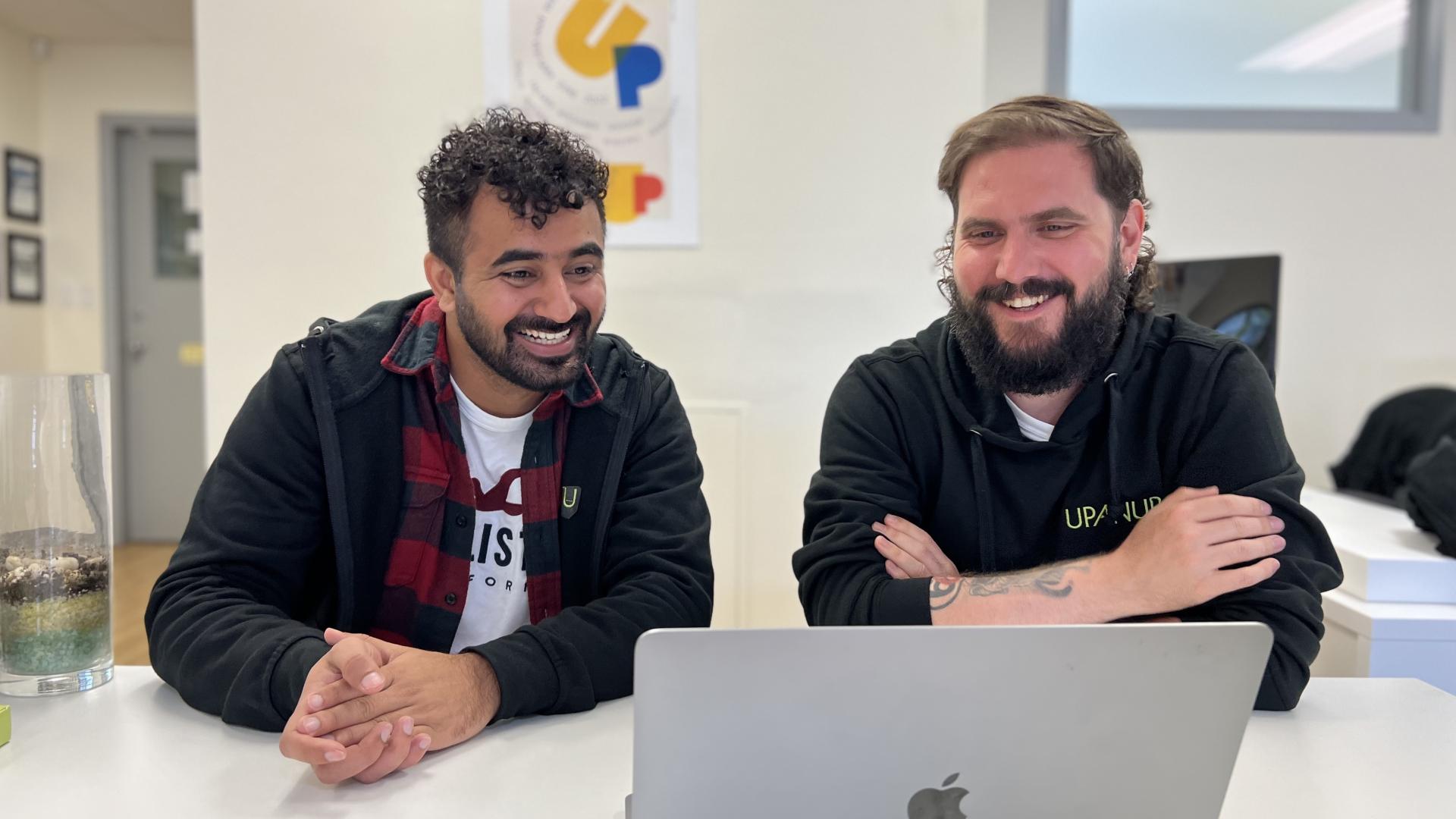 two work colleagues looking at a laptop smiling